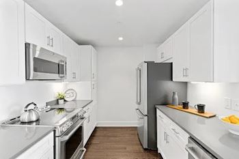 A modern kitchen with white cabinets and stainless steel appliances.